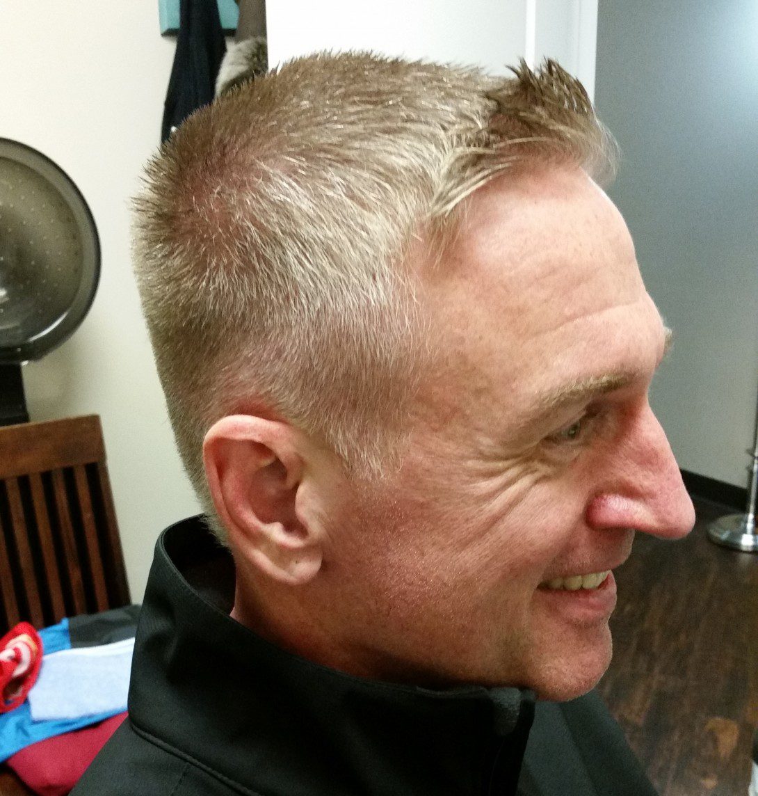 A man with a short haircut is smiling.