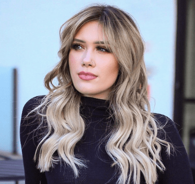 A woman with long blonde hair wearing black.