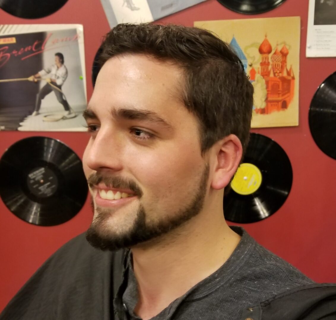 A man with a beard and mustache in front of records.